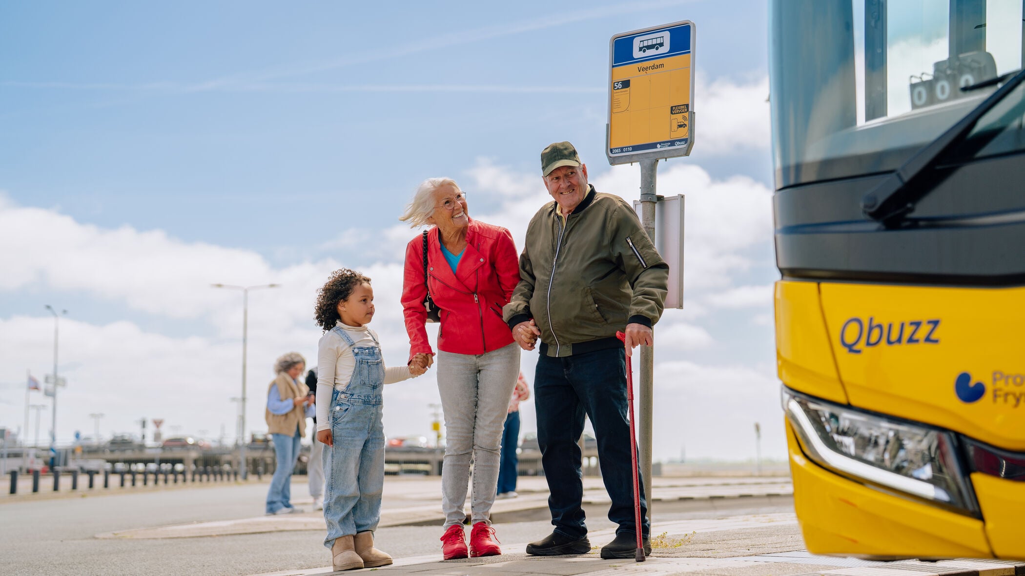 Opa en oma staan met kleinkind bij bushalte